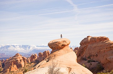 person standing on rocks overlooking desert landscape