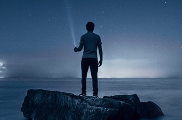long exposure holding flashlight on coastal cliff