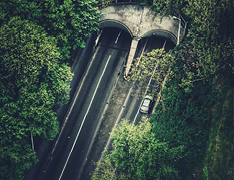 aerial view of car entering forest tunnel