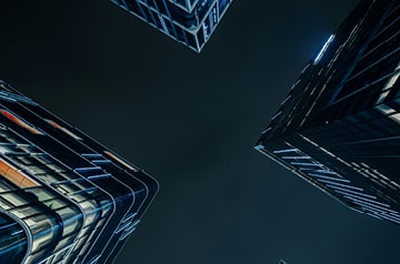 Looking up at the night sky between three skyscrapers.