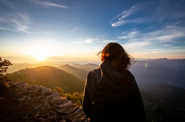 Woman looking over mountain range at sunrise