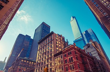 Upward perspective up skyscrapers against a bright blue sky