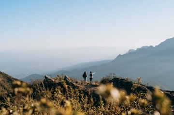 Two hikers on a hilltop looking at the next peak.