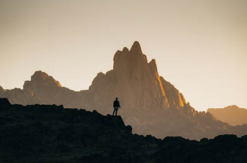 Silhouette of a person standing in front of a distant mountain
