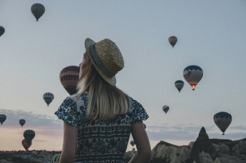 Image of woman looking upwards toward hot air balloons