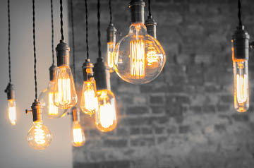 Illuminated decorative lightbulbs hanging in front of a gray brick wall.