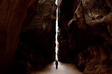 Figure in silhouette standing in a crevice between two large rocks