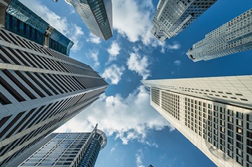 look up at blue sky between skyscrapers