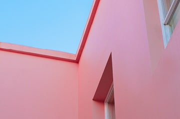 Looking skyward alongside of a bright pink building