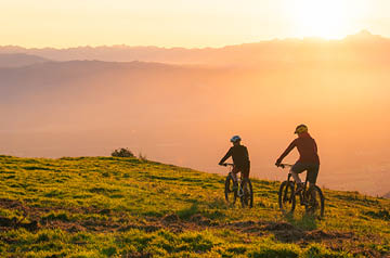 Two mountain bikers in a meadow at sunset