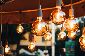 Multiple strings of round outdoor lights hanging from a ceiling.