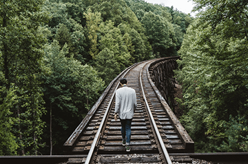 walking on railroad bridge high above forest floor