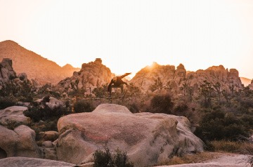 skateboarder doing trick on top of boulder
