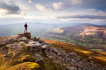 Hiker on outcropping looking over valley