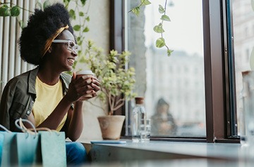 Person holding hot drink looking out window