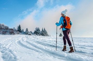 Person hiking on a snowy path using walking poles