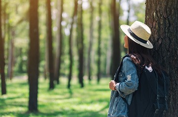 Woman standing in forest looking at trees