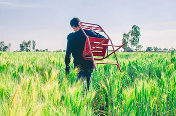 person carrying lawn chair through field